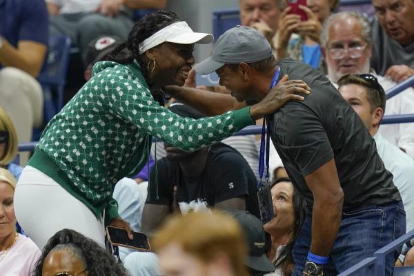 Serena Williams' elder sister, Venus, greets Tiger Woods at the players' box during the American star's second round match at the US Open. (AP)